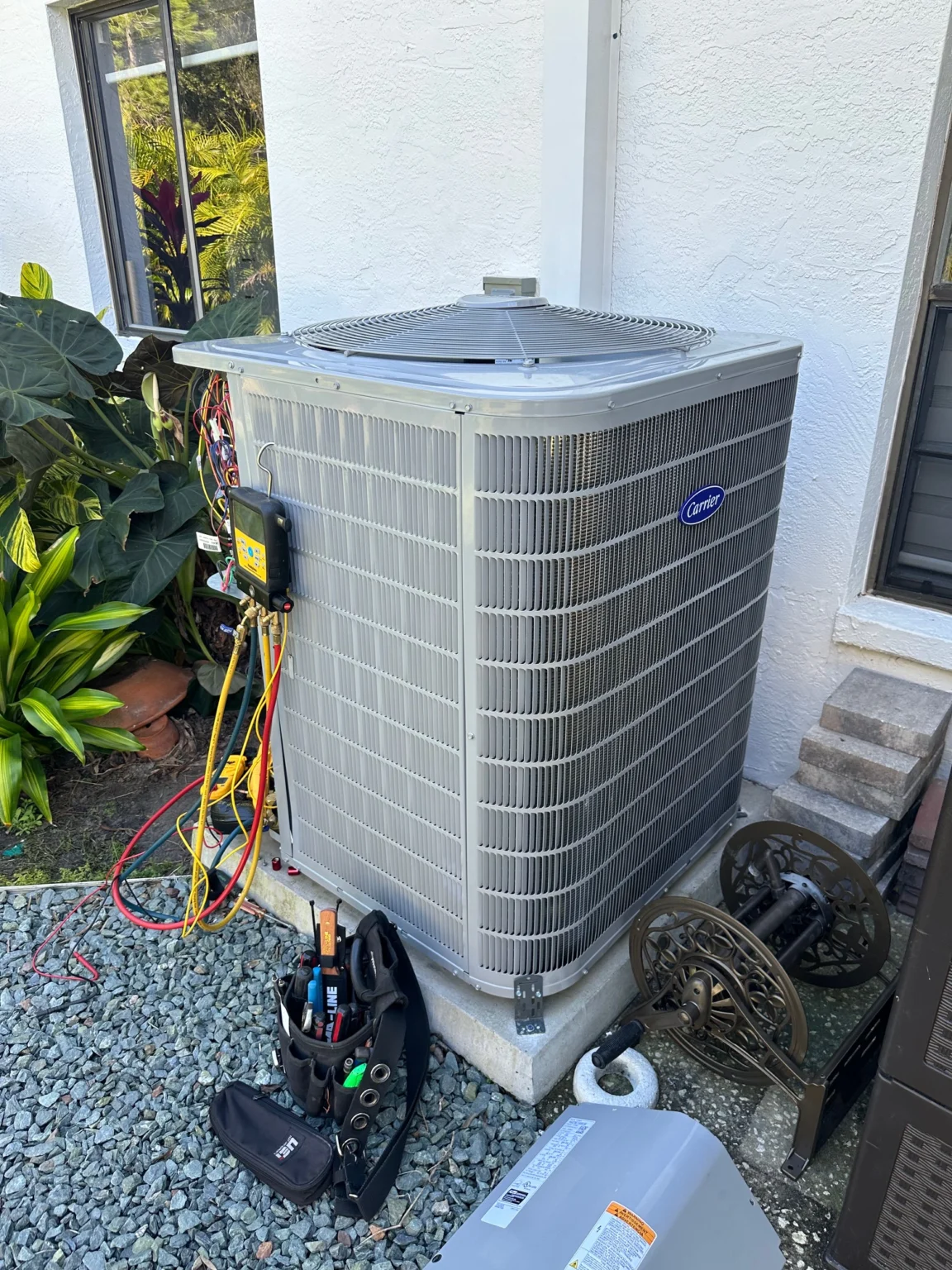Outdoor HVAC condenser unit undergoing maintenance with special equipment attached