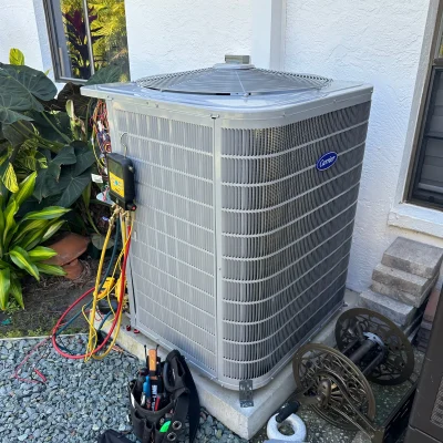 Outdoor HVAC condenser unit undergoing maintenance with special equipment attached